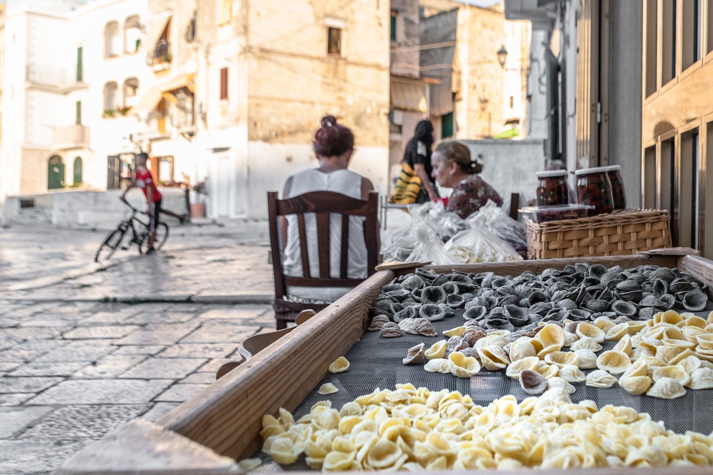 A woman shaping orecchiette by hand on a street table in Bari