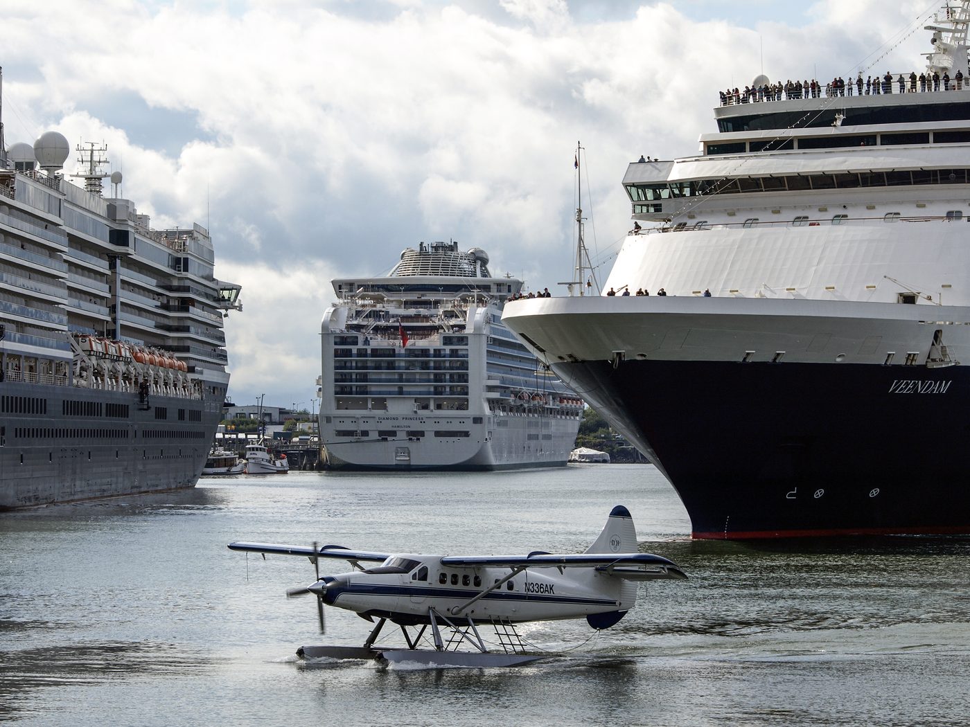 Three cruise ships at the Juneau waterfront with a floatplane overhead