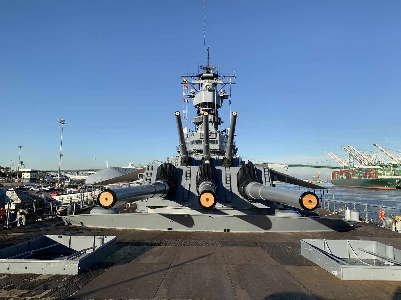 The 16-inch gun turret on the deck of the Battleship Iowa, with harbor cranes behind