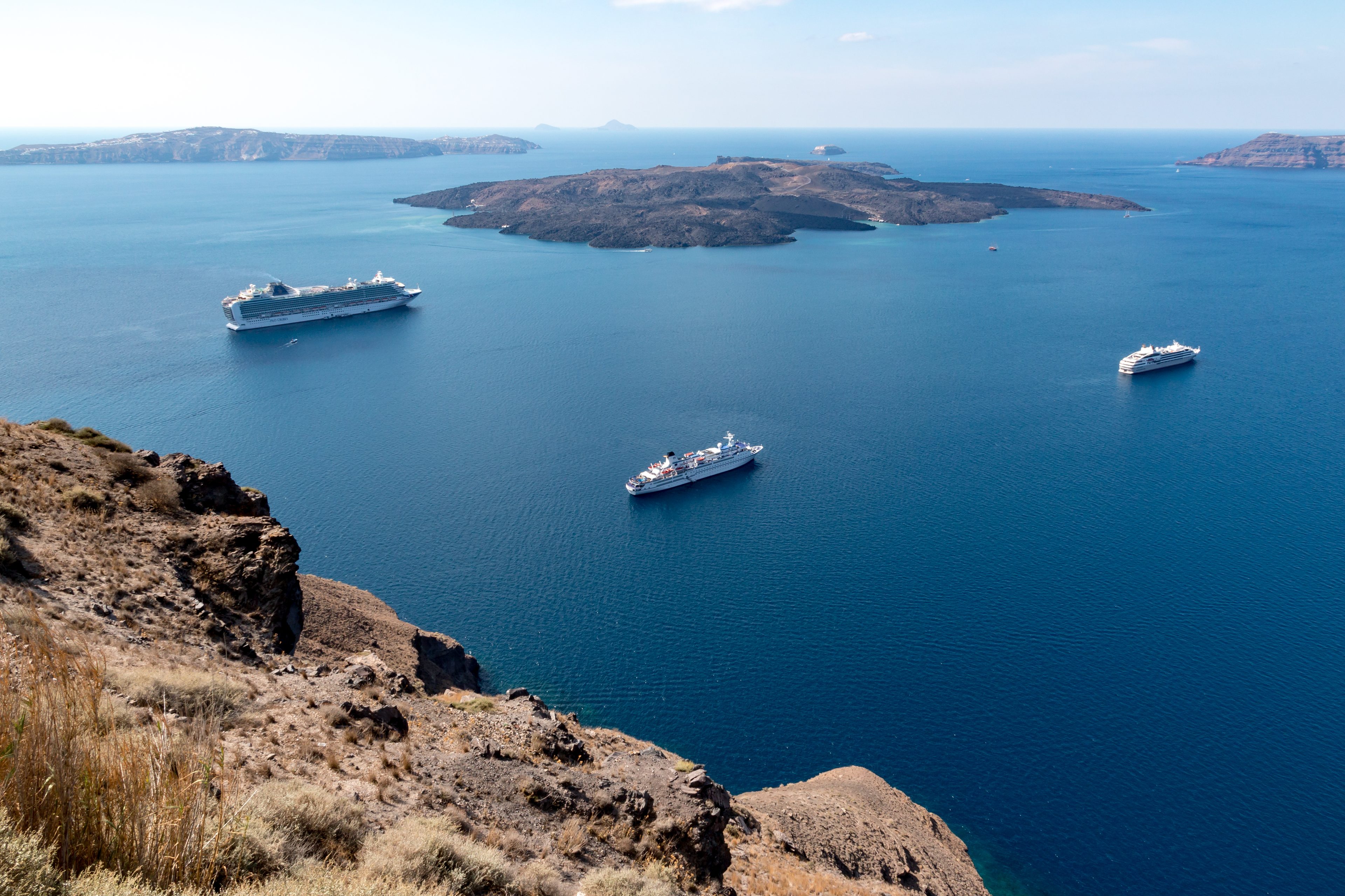 The caldera at Fira on Santorini with three cruise ships at anchor and Nea Kameni beyond