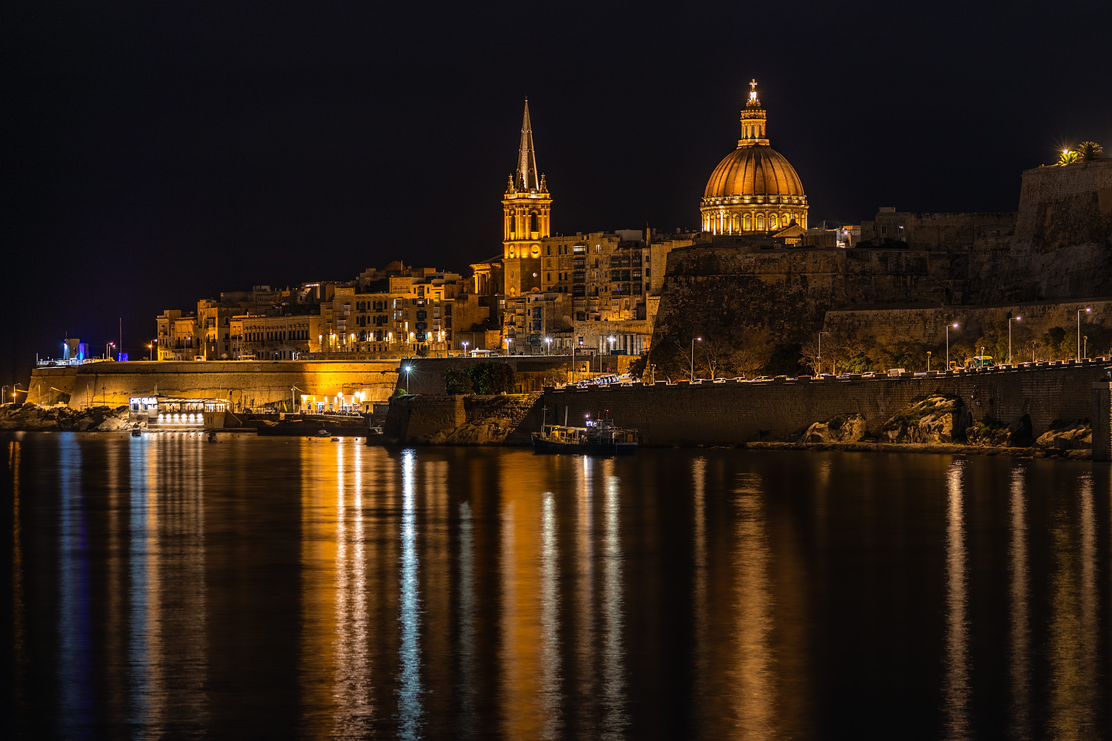The domes and spires of Valletta at night, reflected in the sea